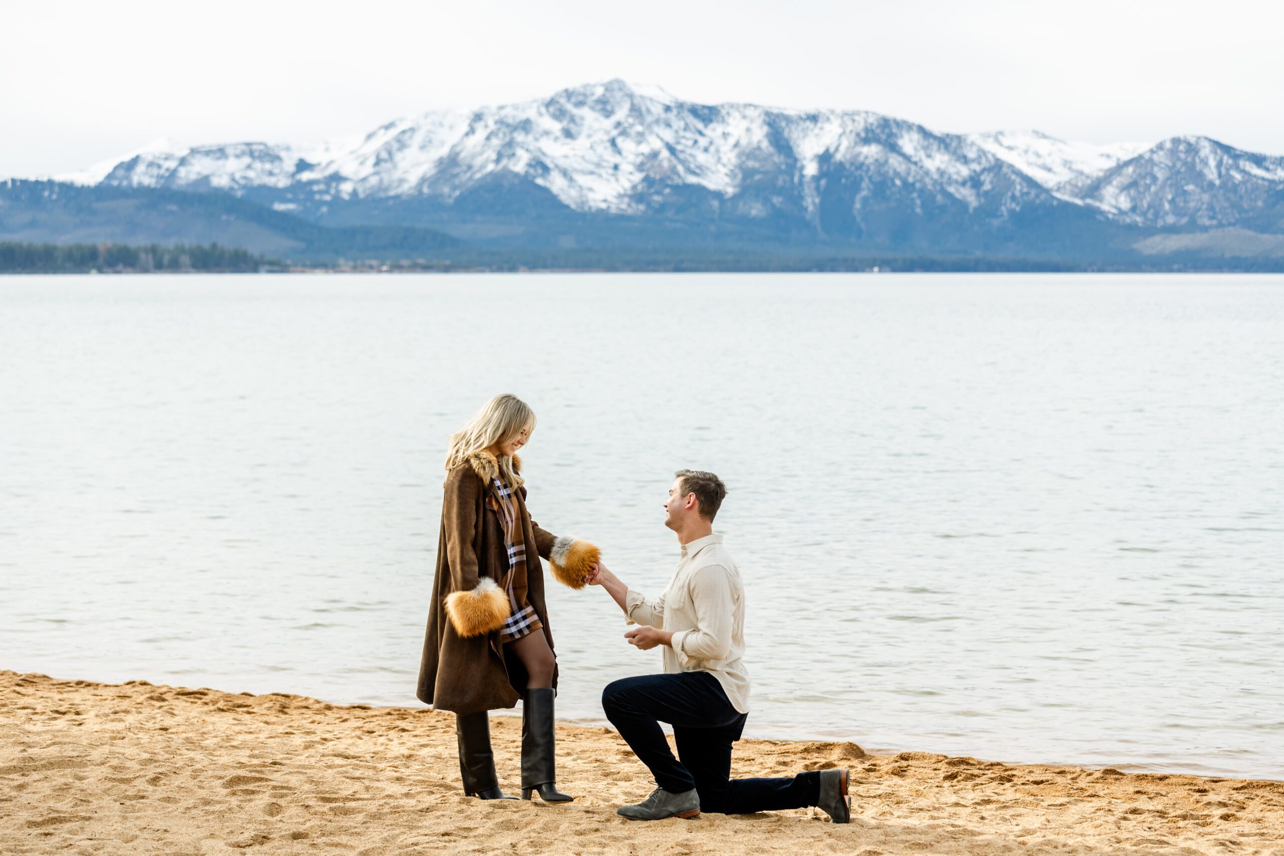 man proposing to girlfriend on the beach in lake tahoe at edgewood in the winter.